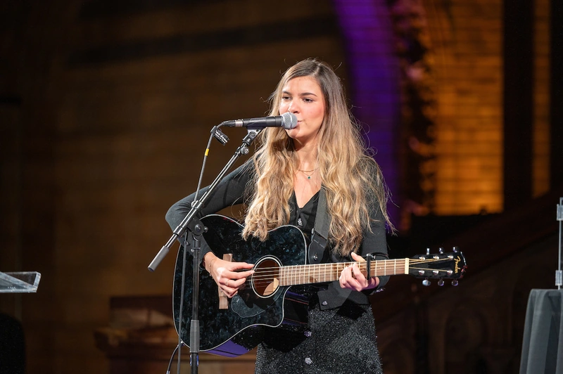 Sirine singing with her guitar at Scope’s gala at the Natural History Museum.